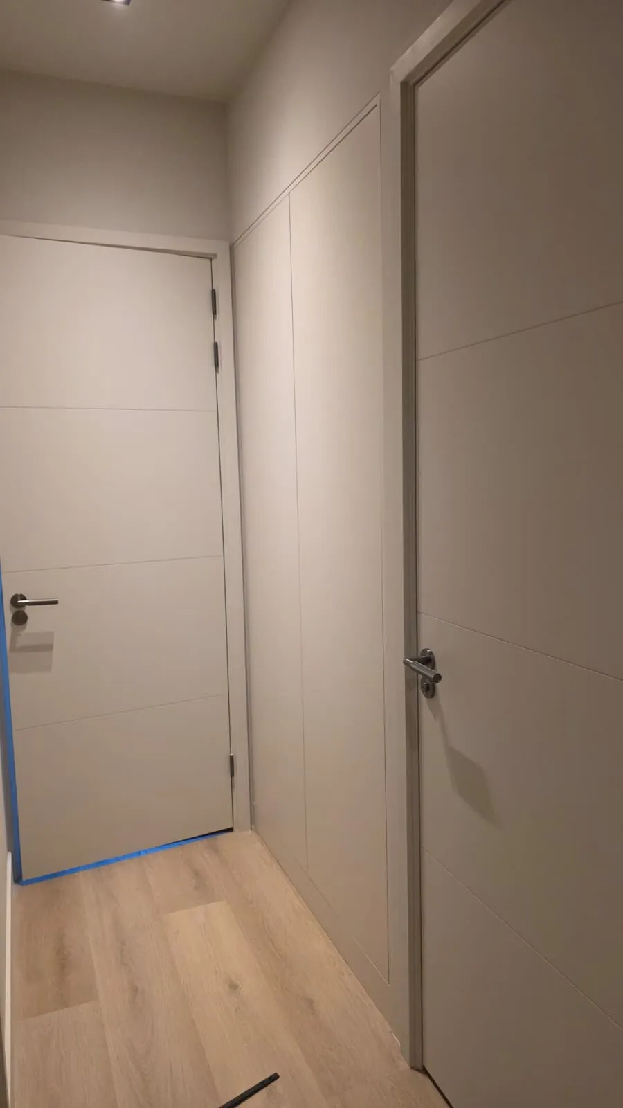 Greeploze kastenwand op maat in een smalle hal, uitgevoerd in een greige tint